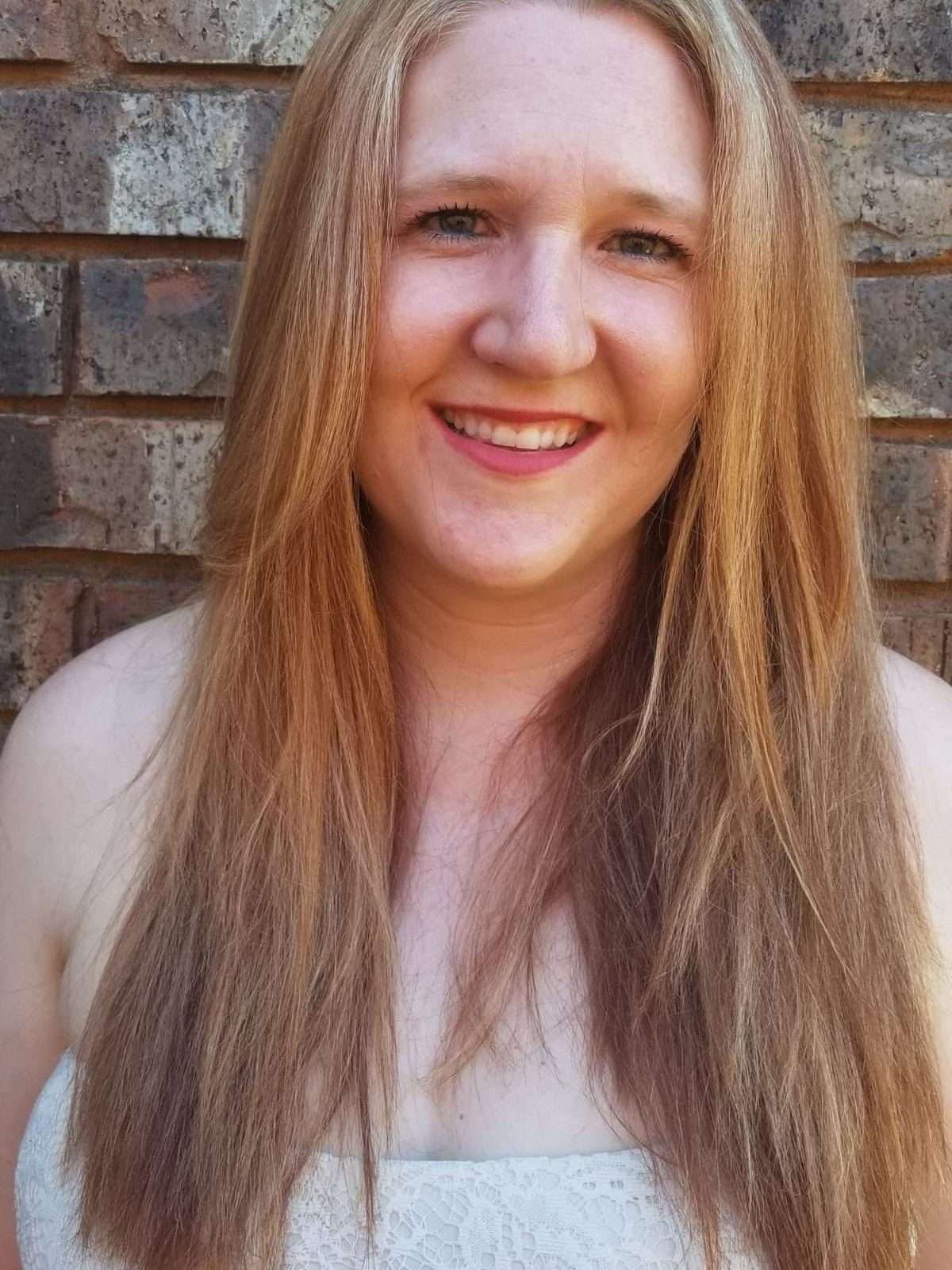 Head Shot of Jenn in front of a brick wall.